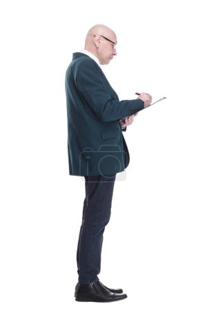 Foto de Vista lateral. Hombre de negocios serio escribiendo algo en el portapapeles. aislado sobre un fondo blanco. - Imagen libre de derechos