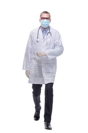 Foto de Caminando joven médico masculino con gafas y máscara quirúrgica. Estudio de larga duración tiro aislado en blanco. - Imagen libre de derechos