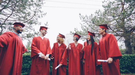 Téléchargez les photos : Heureux diplômés rire et célébrer la remise des diplômes sur le campus de l'université. Éducation, réussite et concept de jeunesse moderne. - en image libre de droit