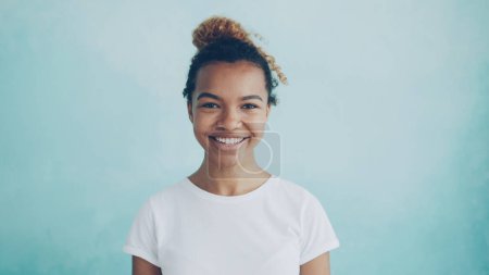 Foto de Retrato de una bonita chica afroamericana mirando a la cámara sonriendo y riendo expresando positividad. Emociones humanas, cambio de humor y concepto juvenil. - Imagen libre de derechos