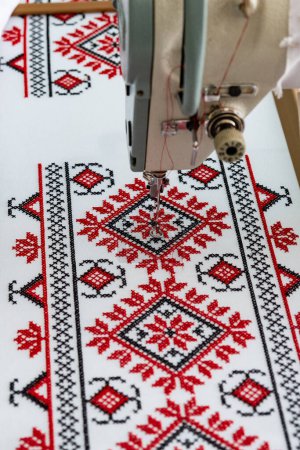 Photo for Machine cross-stitch. Cross-stitch with red and black threads on canvas. Cross stitch on a sewing machine, close-up, selective focus. Ukrainian rushnyk, folk pattern ornament - Royalty Free Image