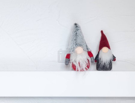 Foto de Elfos, decoraciones navideñas. Navidad Gonks sentarse en un estante de madera blanca contra la pared. Concepto de Navidad y Año Nuevo, tarjeta de felicitación, espacio para copiar - Imagen libre de derechos