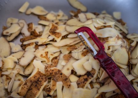Foto de Cáscaras de patatas frescas y un pequeño cuchillo de verduras. Residuos biodegradables domésticos. Vista desde arriba - Imagen libre de derechos
