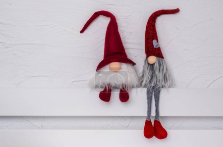 Téléchargez les photos : Gonks scandinaves au chapeau rouge. Gnomes de Noël sur l'étagère en bois blanc. Espace libre pour le texte. Noel ou Nouvel An concept, carte de voeux - en image libre de droit