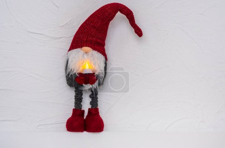 Foto de Gnomo de Navidad - Gonk con barba larga y sombrero rojo en el estante de madera blanca. Concepto de Navidad y Año Nuevo, tarjeta de felicitación, espacio para copiar - Imagen libre de derechos