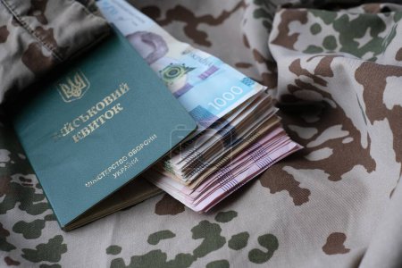 Ukrainischer Militärausweis und Griwna auf Militäruniform. Zahlungen an Soldaten der ukrainischen Armee, Gehälter an das Militär. Krieg in der Ukraine