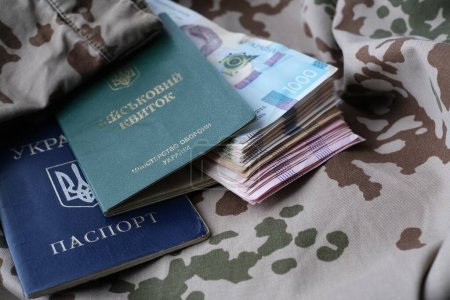 Carte d'identité militaire ukrainienne et hryvnia en uniforme militaire. Paiements aux soldats de l'armée ukrainienne, salaires aux militaires. Guerre en Ukraine