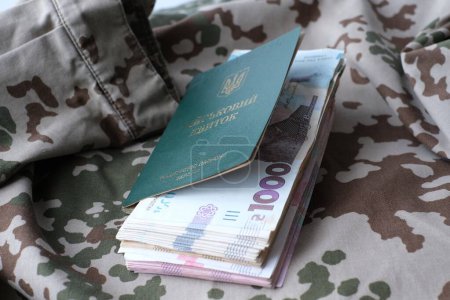 Ukrainian military ID and hryvnia on military uniform. Payments to soldiers of the Ukrainian army, salaries to the military. War in Ukraine