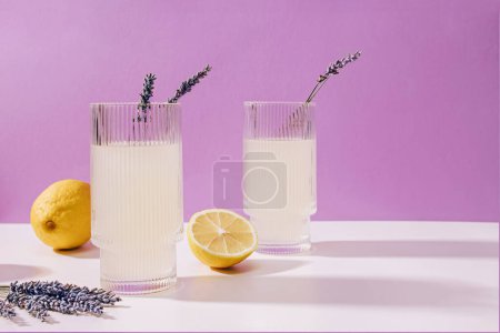 Two ribbed glasses with lavender lemonade over purple background, summer refreshing drink