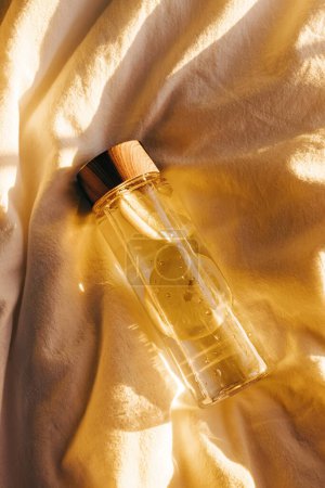 Photo for Reusable bottle with lemon infused water in warm natural light on the bed, self-care and wellness. - Royalty Free Image