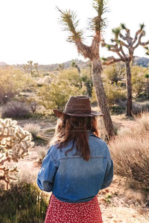 Photo for A woman wearing a hat and denim shirt explores the desert, travel and outdoor exploration - Royalty Free Image