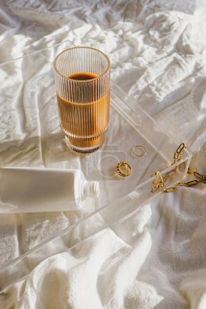 Photo for Iced coffee and jewelry on the tray, morning routine aesthetic still life in natural light - Royalty Free Image