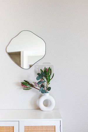 Photo for Minimalist home decor. Sandstone donut-shape vase on the dresser and organic fluid shape mirror on the wall - Royalty Free Image