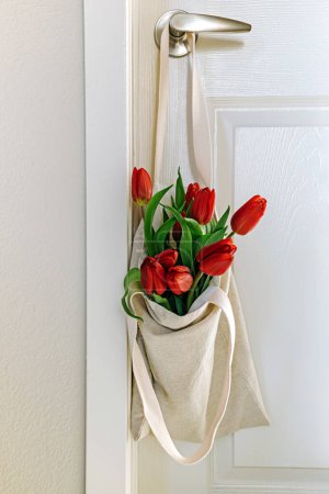 Photo for Red tulips in a hanging reusable bag, spring lifestyle composition - Royalty Free Image