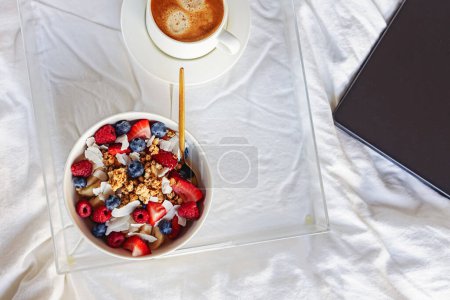 Photo for Breakfast with yogurt granola bowl topped with berries and coffee, view from the top - Royalty Free Image