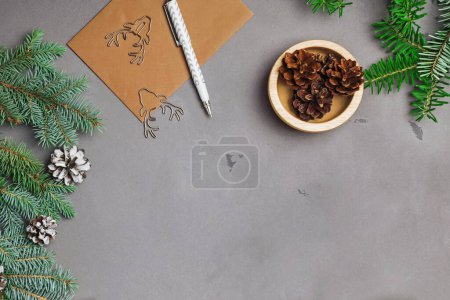Photo for Fir branches, pine cones and envelope on grey stone surface, top view, Christmas background - Royalty Free Image
