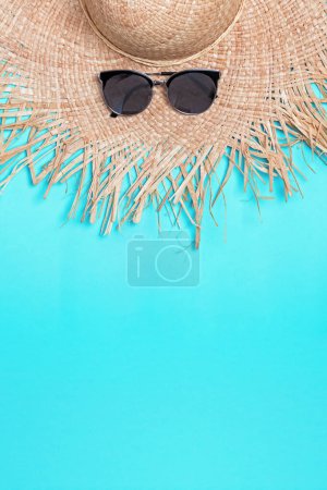 Photo for Straw hat with wide fields and sunglasses on blue background with copy space - Royalty Free Image