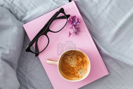 Photo for Composition with pink mug with coffee, pink notepad or diary and glasses on the bed, overhead view - Royalty Free Image