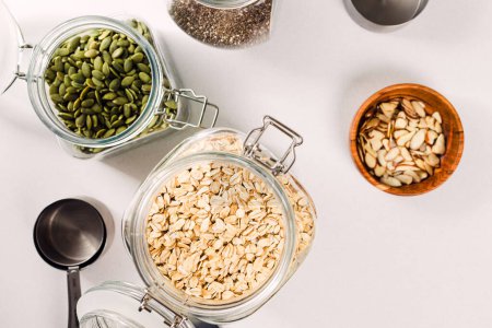 Photo for Oatmeal, chia and pumpkin seeds in a glass jars, ingredients to prepare granola or overnight oats - Royalty Free Image