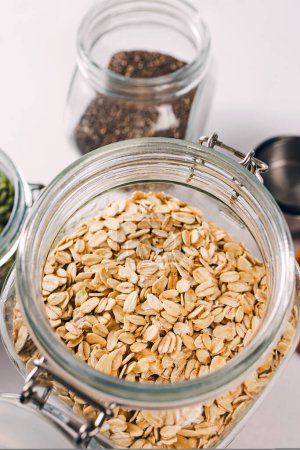 Photo for Close-up view of a glass jar full of rolled oats, healthy nutrition - Royalty Free Image