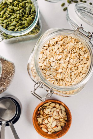 Photo for Oatmeal, chia and pumpkin seeds in a glass jars, ingredients to prepare granola or overnight oats - Royalty Free Image