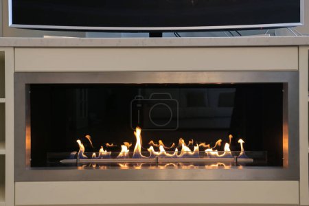 Burning eco bio ethanol fireplace built into furniture under TV