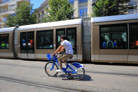 Photo for Nice, France - 24 July, 2019:  A man rides a bike in front of a tram in the Nice - Royalty Free Image