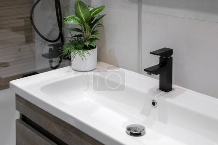 Photo for Black faucet with white ceramic sink in the bathroom - Royalty Free Image