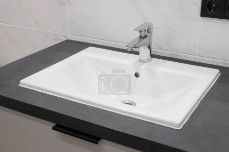 Photo for Chrome faucet with white ceramic sink in the bathroom interior - Royalty Free Image