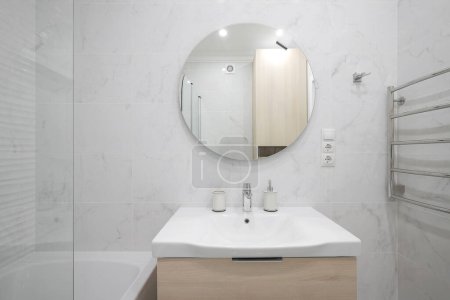 Foto de Grifo con lavabo de cerámica y espejo redondo en el interior del baño - Imagen libre de derechos