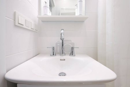 Robinet chromé avec évier en céramique blanche à l'intérieur de la salle de bain