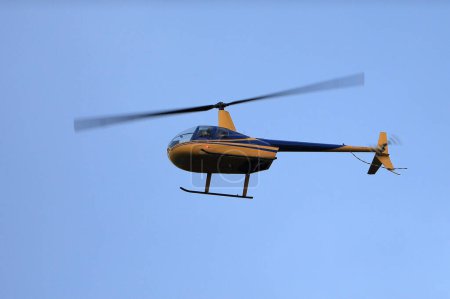 Foto de Helicóptero Robinson R44 vuela en el cielo azul - Imagen libre de derechos