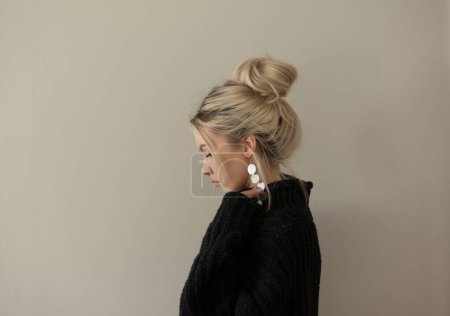 Foto de Hermosa joven con suéter negro cálido y joyas de moda sobre fondo pastel. Estilo estético minimalista de moda. - Imagen libre de derechos