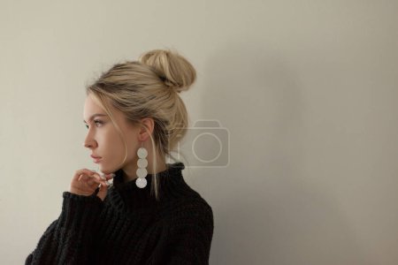 Téléchargez les photos : Belle jeune fille portant un pull noir chaud et des bijoux de mode sur fond pastel. Style esthétique minimaliste tendance. - en image libre de droit