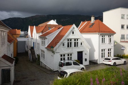 Foto de Casas de madera típicas noruegas blancas en una calle de Bergen contra un cielo dramático, Noruega - Imagen libre de derechos