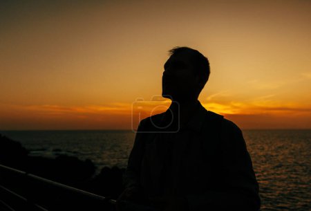 Die Silhouette eines Mannes, der das Leben betrachtet, wird vor dem hellen Sonnenuntergang auf der Insel Teneriffa, Spanien, skizziert..