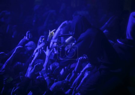 Téléchargez les photos : Silhouette du chanteur de rap cool se produisant sur scène dans une boîte de nuit sombre. Rappeur en sweat à capuche performant sur scène - en image libre de droit