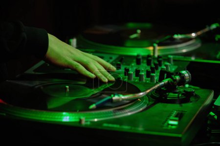 Hip hop dj scratches vinyl records on party in night club. Disc jockey scratching vinyls on turntable player device