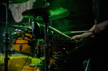 Téléchargez les photos : Le batteur joue de la batterie sur scène de concert rock sous les feux verts. Musicien professionnel en concert au music-hall - en image libre de droit