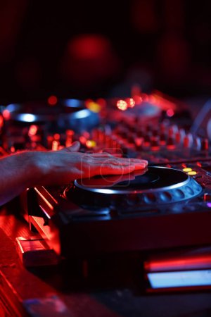 Party dj playing music in night club with professional cd turntables. Disc jockey mixing musical tracks on concert stage
