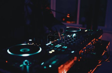 Foto de Dj toca música ambientada en una fiesta rave en un club nocturno. Disco jockey tocando pistas musicales con mezclador de sonido y tocadiscos en el escenario de concierto. - Imagen libre de derechos