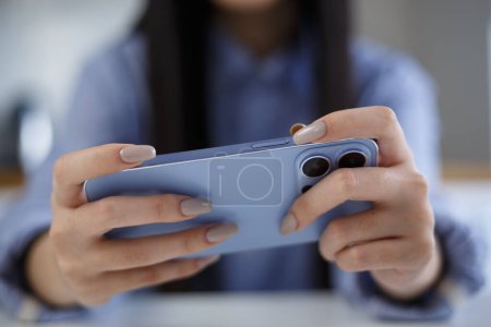 Téléchargez les photos : Gamer girl plays online game on smartphone. Young female playing videogames on gadget - en image libre de droit