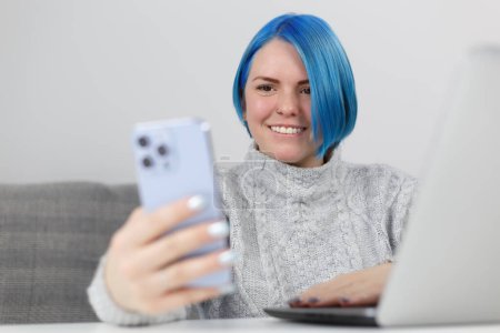 Téléchargez les photos : Friendly millennial woman with dyed blue hair communicating on video call. Freelancer female person networking with clients online - en image libre de droit