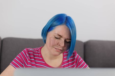 Foto de Portrait of millennial woman with dyed blue hair working on computer at home. Freelance writer person typing text on laptop - Imagen libre de derechos