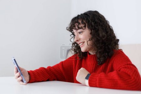 Téléchargez les photos : Happy young girl talks on frontal camera. Cheerful Ukrainian female speaking on smart phone video call - en image libre de droit