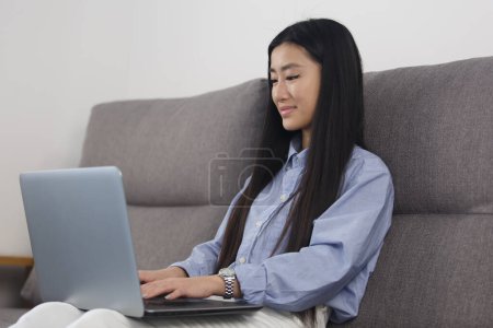 Photo for Vietnamese POC girl typing code on computer. Cheerful BIPOC female coding on modern laptop at home. Freelance programmer person works online - Royalty Free Image