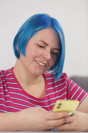 Téléchargez les photos : Portrait of cheerful blue haired woman browsing yellow mobile phone. Cheerful millennial female person using modern smart phone - en image libre de droit