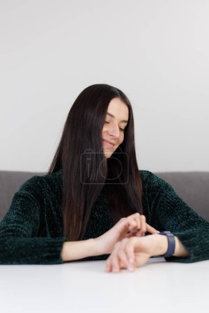 Foto de Cheerful Ukrainian woman browsing messages on smart watches. Brunette female using modern smartwatch gadget with a smile - Imagen libre de derechos