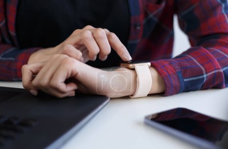 Foto de Person using smart wrist watches. Young female browsing notifications and messages on modern smartwatch gadget - Imagen libre de derechos
