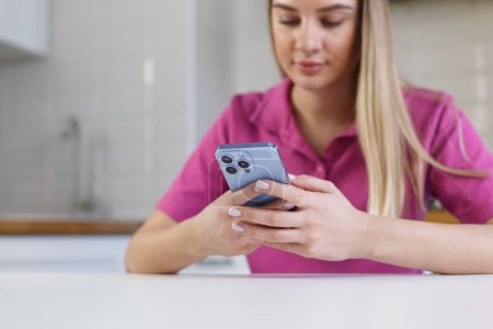 Foto de Young blonde woman typing a message in messenger app on modern blue smart phone. Blonde girl texting with a mobile phone - Imagen libre de derechos